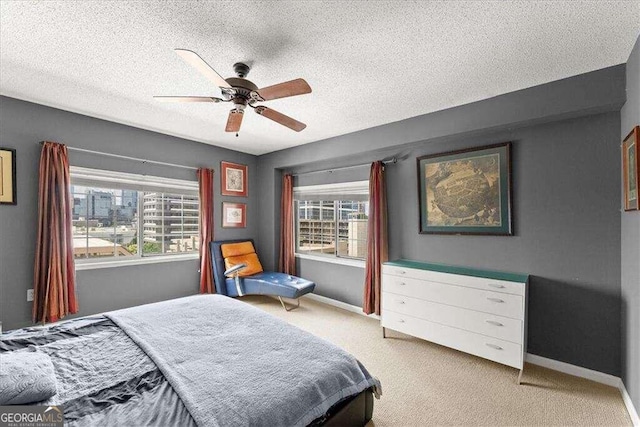 bedroom with a textured ceiling, baseboards, a ceiling fan, and light colored carpet