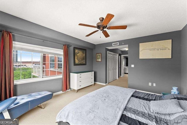 bedroom featuring a textured ceiling, carpet floors, a ceiling fan, visible vents, and baseboards