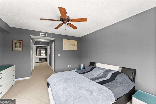 bedroom featuring a textured ceiling, visible vents, a ceiling fan, and light colored carpet