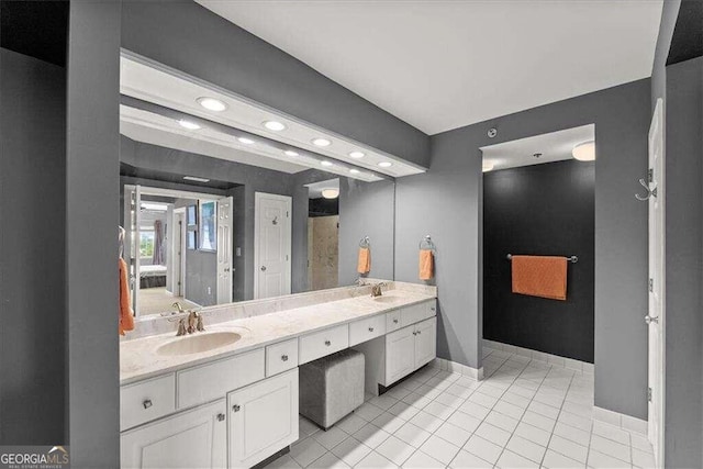 bathroom featuring tile patterned flooring, a sink, baseboards, and double vanity