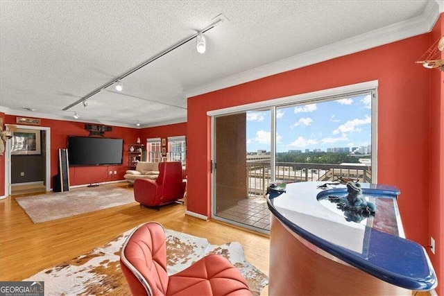 living room with a textured ceiling, ornamental molding, and wood finished floors