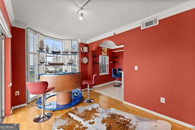 interior space with visible vents, arched walkways, wood finished floors, and ornamental molding