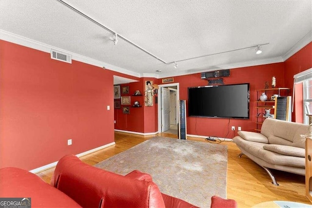 living area with visible vents, wood finished floors, a textured ceiling, and ornamental molding