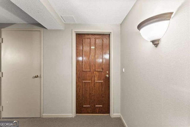 interior space with a textured ceiling, carpet flooring, and baseboards