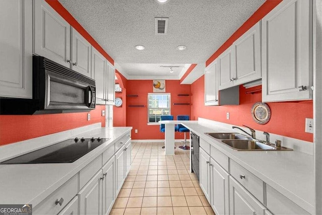 kitchen with a textured ceiling, a sink, visible vents, light countertops, and black appliances