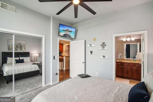 bedroom featuring ensuite bath, ceiling fan, sink, light colored carpet, and a closet