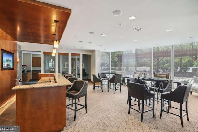 carpeted dining space featuring a wall of windows and wooden walls