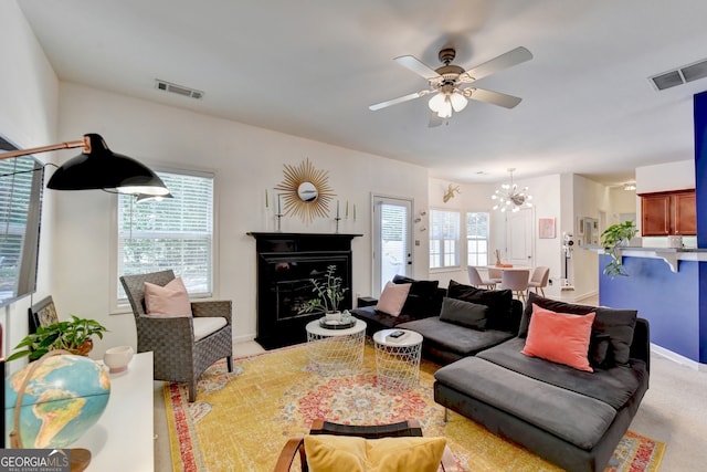 carpeted living room featuring ceiling fan with notable chandelier