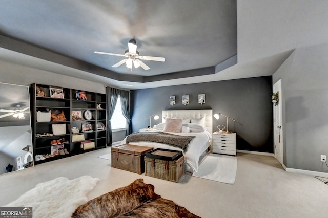 bedroom featuring a raised ceiling, ceiling fan, and carpet