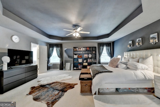 bedroom with carpet flooring, ceiling fan, and a raised ceiling