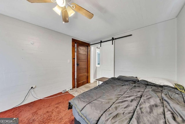 bedroom featuring a barn door, ceiling fan, and carpet flooring