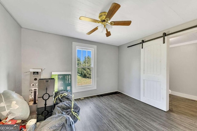 unfurnished office featuring a barn door, dark hardwood / wood-style floors, and ceiling fan