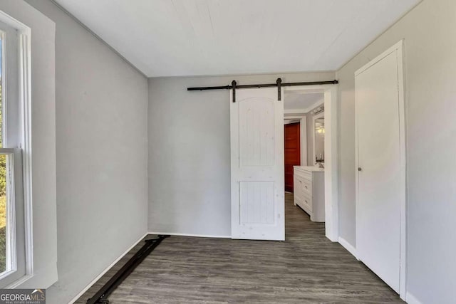 unfurnished room featuring dark wood-type flooring and a barn door