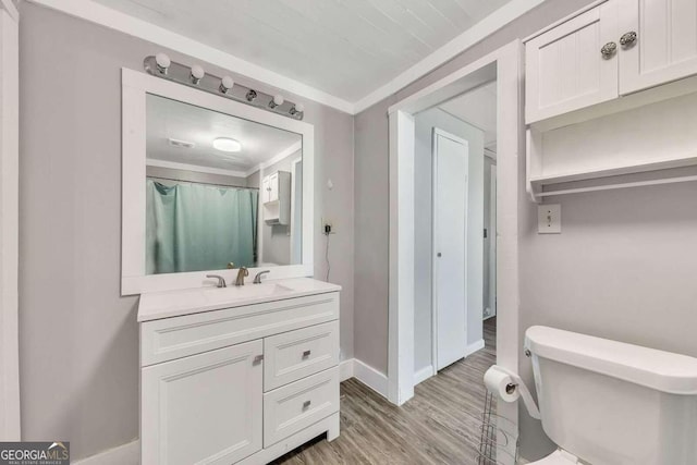 bathroom with hardwood / wood-style flooring, vanity, crown molding, and toilet