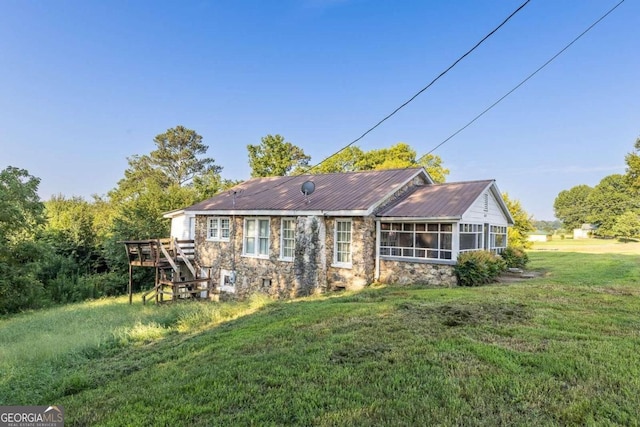 back of property with a sunroom and a lawn