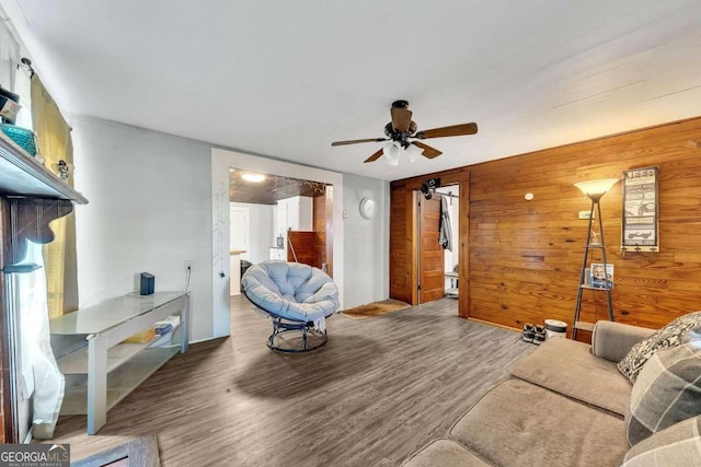 living room with hardwood / wood-style flooring, ceiling fan, and wooden walls