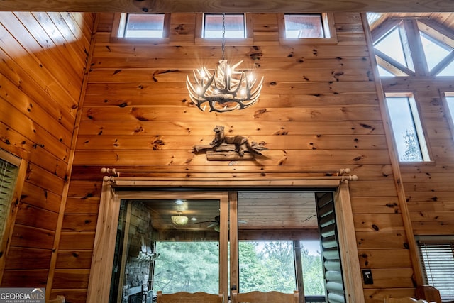 interior details featuring an inviting chandelier and wood walls