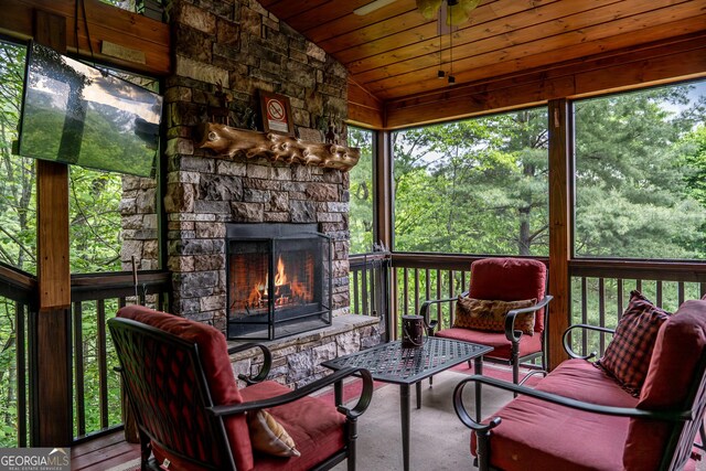 sunroom / solarium with wood ceiling, a stone fireplace, and vaulted ceiling