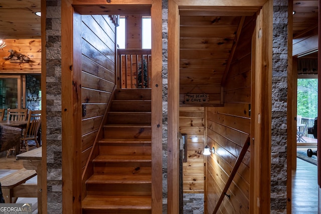 stairway featuring lofted ceiling, wood ceiling, and wood walls