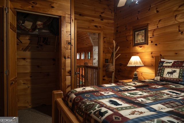 carpeted bedroom with ceiling fan, wood walls, and a closet