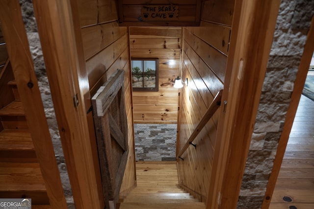 staircase featuring wooden walls and hardwood / wood-style floors