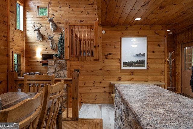 dining space with hardwood / wood-style flooring, wooden walls, and wooden ceiling