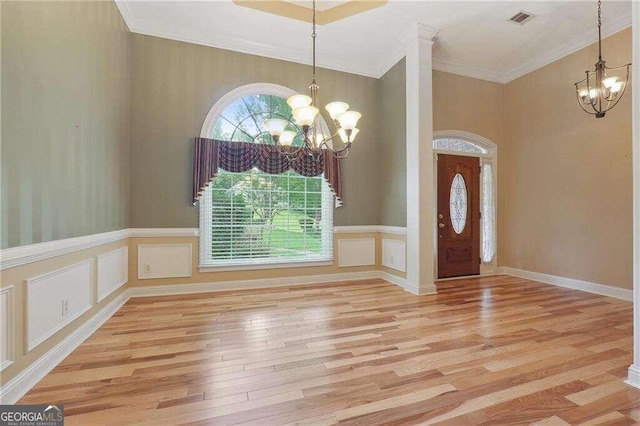 foyer entrance featuring crown molding, light hardwood / wood-style flooring, and a chandelier