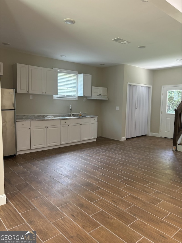 kitchen with white cabinets, dark hardwood / wood-style floors, sink, and stainless steel refrigerator