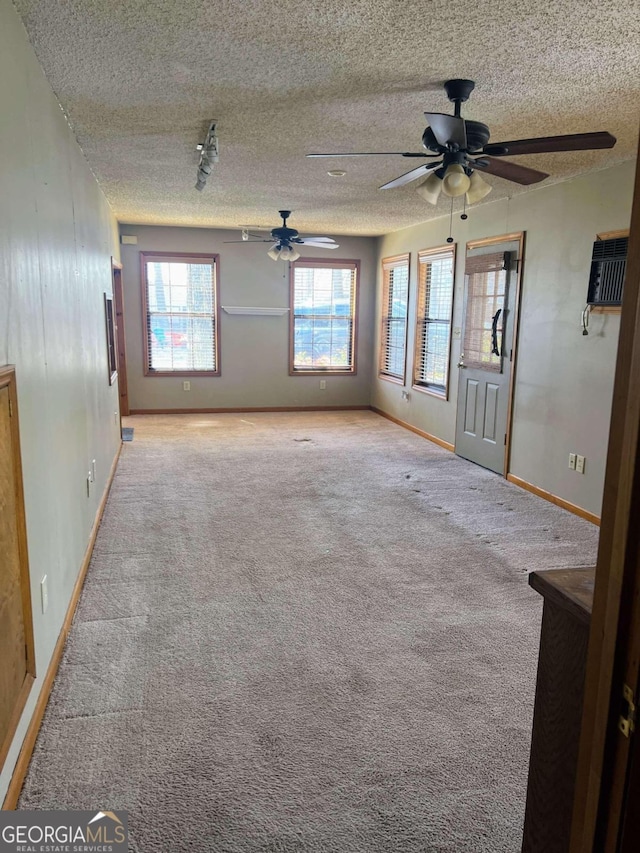 empty room featuring a textured ceiling, light colored carpet, and ceiling fan