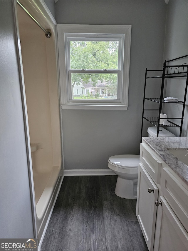 bathroom with vanity, toilet, wood-type flooring, and a shower