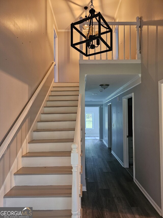 stairway with ornamental molding, dark hardwood / wood-style flooring, and a chandelier