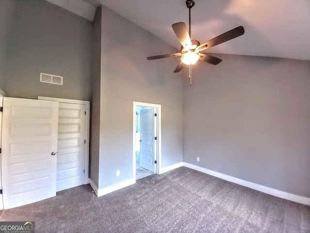 unfurnished bedroom featuring a closet, high vaulted ceiling, dark carpet, and ceiling fan