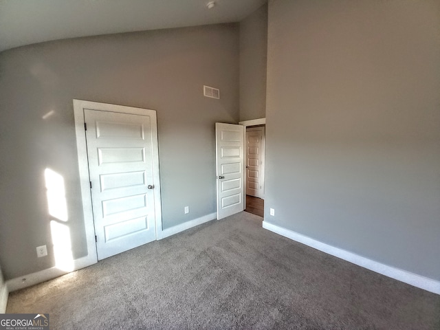 unfurnished bedroom featuring high vaulted ceiling and carpet flooring