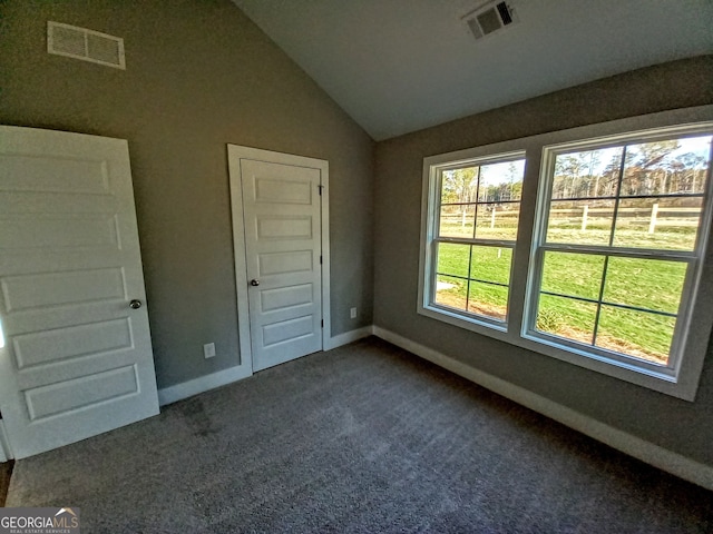 unfurnished bedroom with dark carpet and lofted ceiling