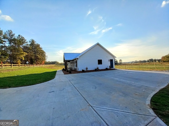 view of side of home featuring a rural view and a yard