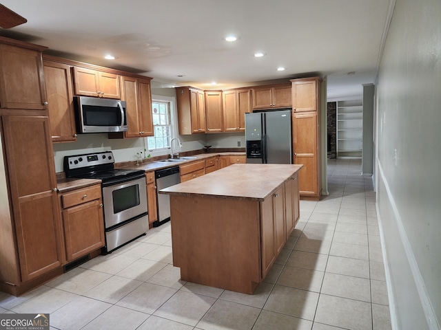 kitchen with appliances with stainless steel finishes, sink, light tile patterned floors, and a kitchen island