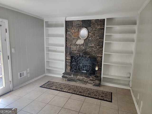 unfurnished living room with a stone fireplace, ornamental molding, light tile patterned floors, and wood walls