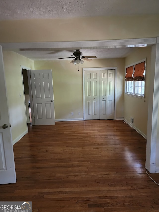 unfurnished bedroom featuring a textured ceiling, dark wood-type flooring, and ceiling fan