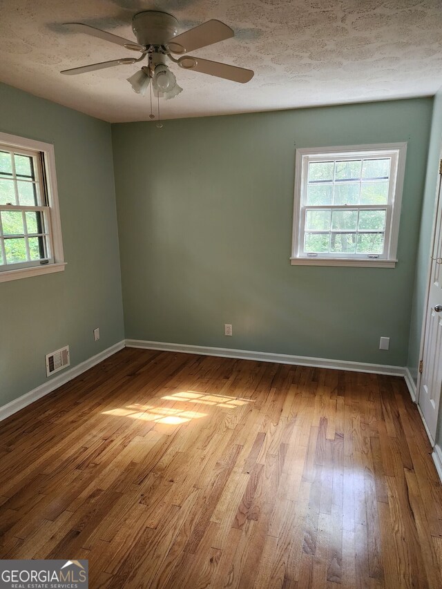 spare room with wood-type flooring, plenty of natural light, and ceiling fan