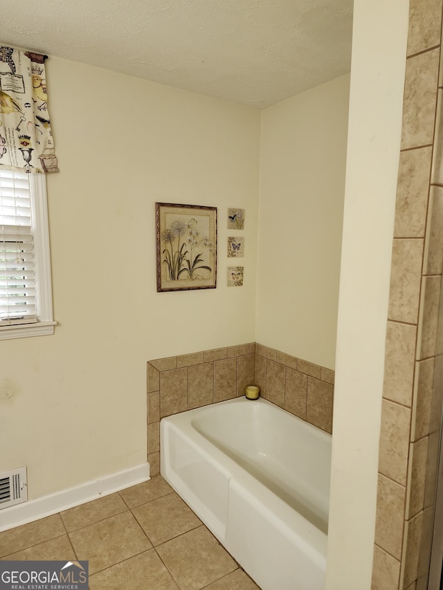 bathroom with a tub, a textured ceiling, and tile patterned flooring