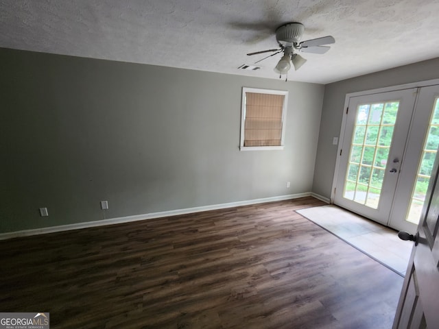 empty room featuring french doors, dark wood-type flooring, a textured ceiling, and ceiling fan