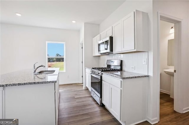 kitchen with an island with sink, white cabinetry, dark hardwood / wood-style floors, and stainless steel appliances