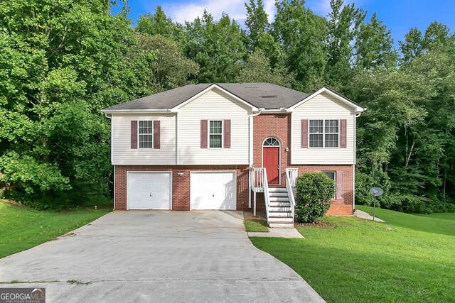 raised ranch featuring a garage and a front lawn