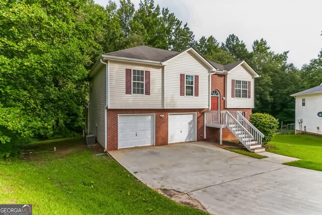 split foyer home featuring a garage, a front lawn, and cooling unit