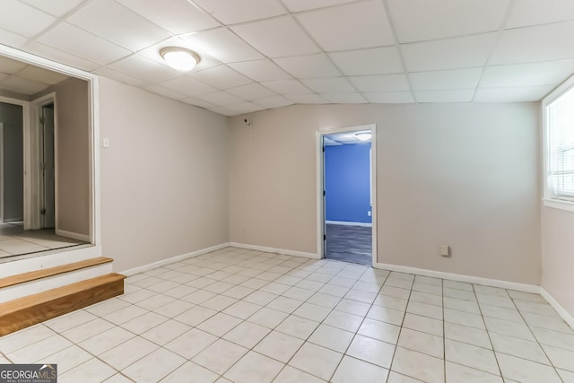 tiled spare room featuring a drop ceiling