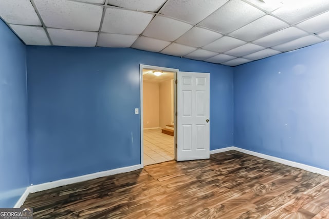 unfurnished room with a paneled ceiling and wood-type flooring