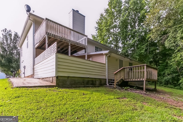 back of property featuring a wooden deck and a lawn