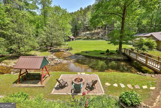 view of yard with a water view, a patio area, and an outdoor fire pit