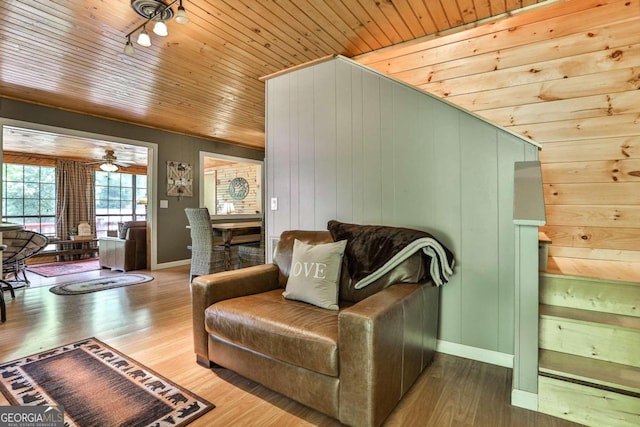 living room with wooden walls, hardwood / wood-style flooring, wood ceiling, and ceiling fan