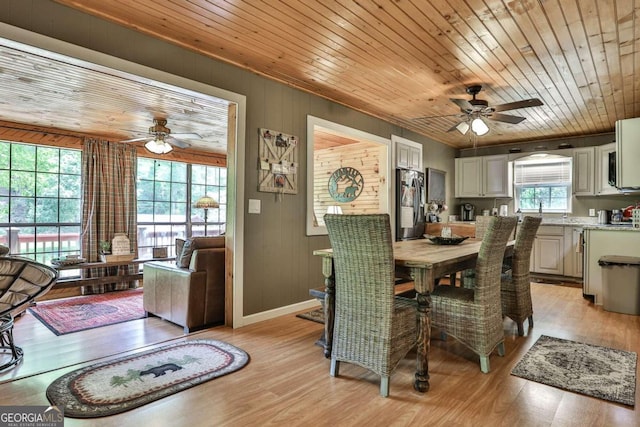 dining space featuring light hardwood / wood-style floors, a wealth of natural light, and wooden ceiling